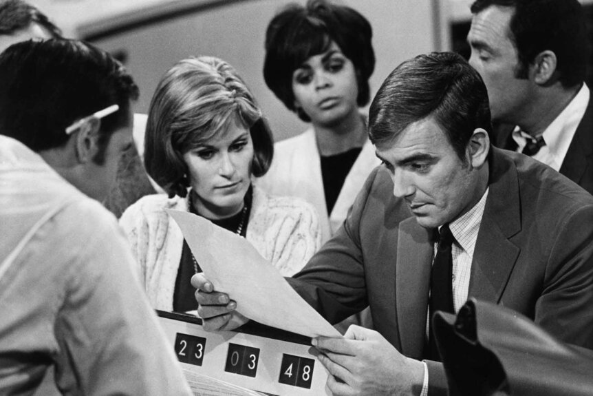 Eric Braeden reading the paper while researchers look on in The Forbin Project (1970).