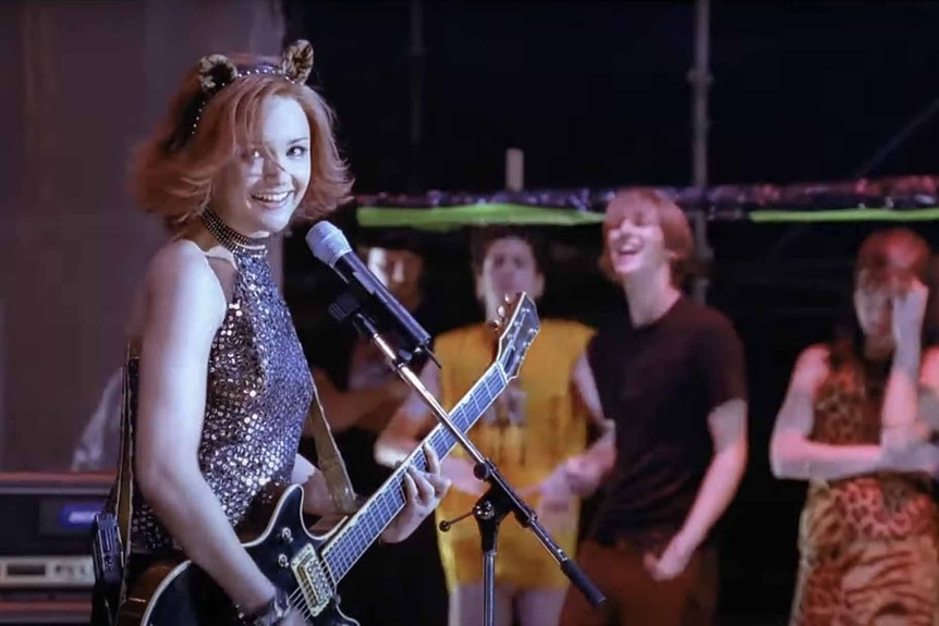Josie (Rachael Leigh Cook) sings and plays the guitar in Josie and the Pussycats (2001).